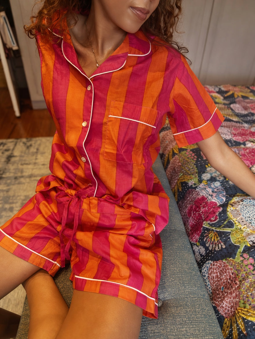Person wearing a pink and orange striped pajama set sitting on a couch.